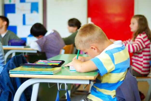 Niño lindo rubio en la escritura de aula