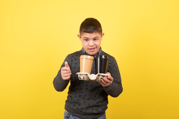 niño lindo con síndrome de down con tazas de café de pie.