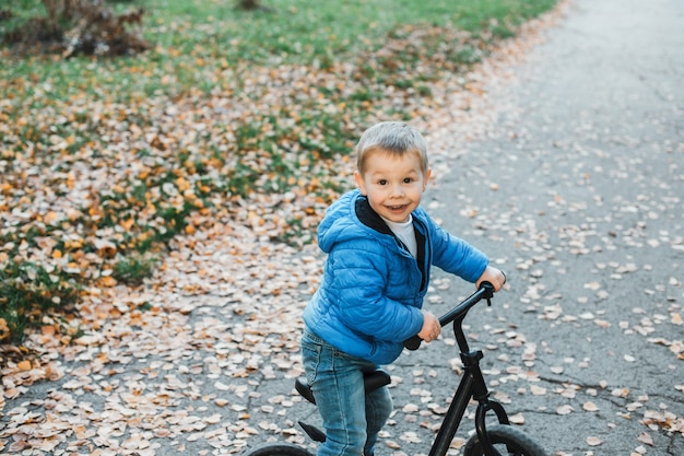 Niño lindo sonriendo mientras monta una bicicleta al aire libre.