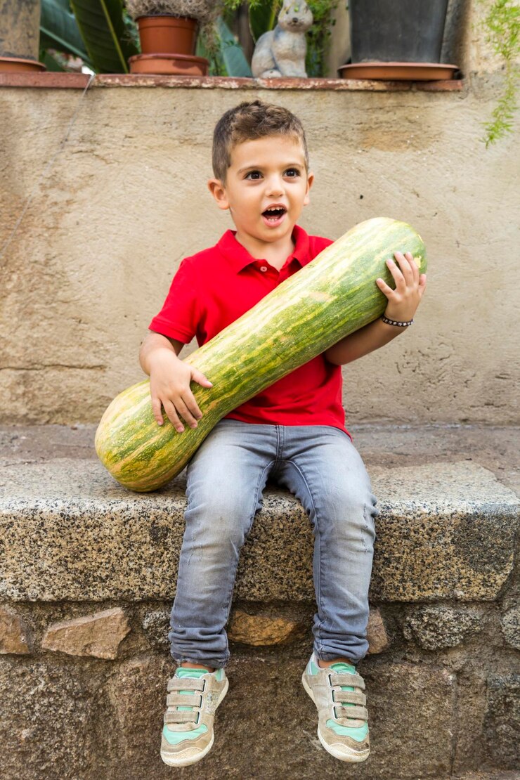 Foto niño lindo sosteniendo una calabaza mientras está sentado en la pared de contención