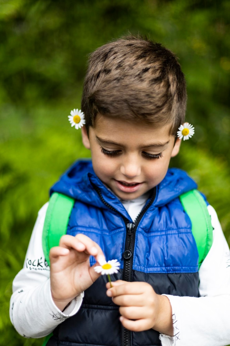 Foto niño lindo sosteniendo una flor mientras está de pie al aire libre