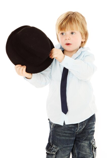 Foto niño lindo sosteniendo un sombrero mientras está de pie contra un fondo blanco