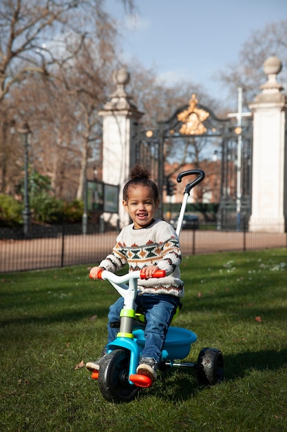 Foto niño lindo de tiro completo sentado en triciclo