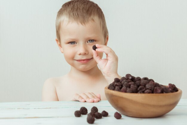 Niño lindo toma suavemente moras en su mano