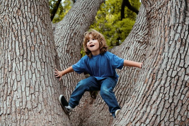 Foto niño lindo trepando al árbol en la naturaleza niños jugando al aire libre