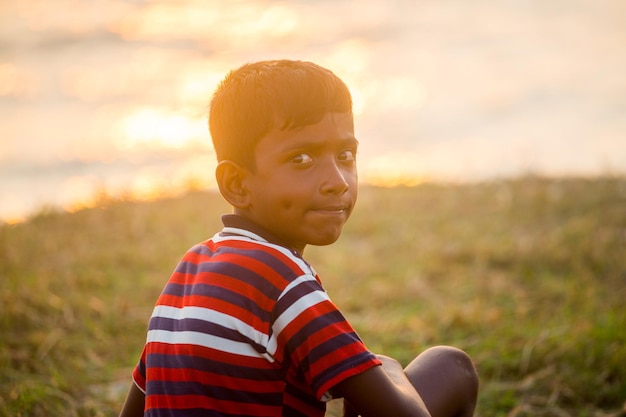 Un niño lisiado sentado en el río mirando la puesta de sol Un día que termina Triste historia