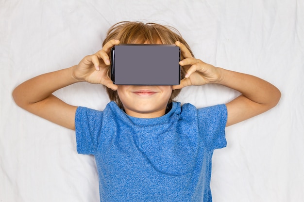 Foto niño liying en cama blanca con realidad virtual 3d