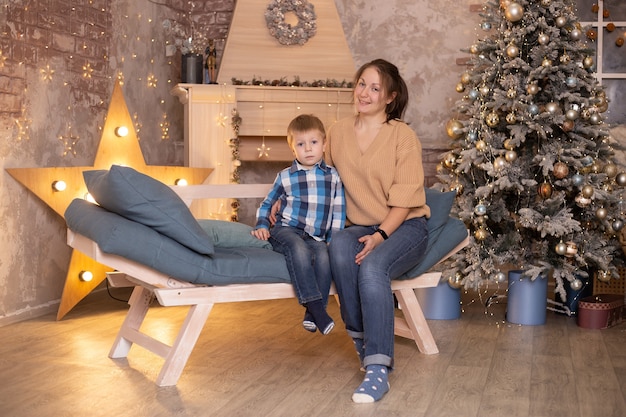 Niño y madre cerca del árbol de Navidad en casa