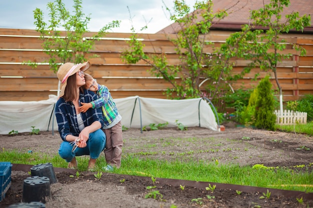 Niño y madre de jardinería en huerta en el patio trasero