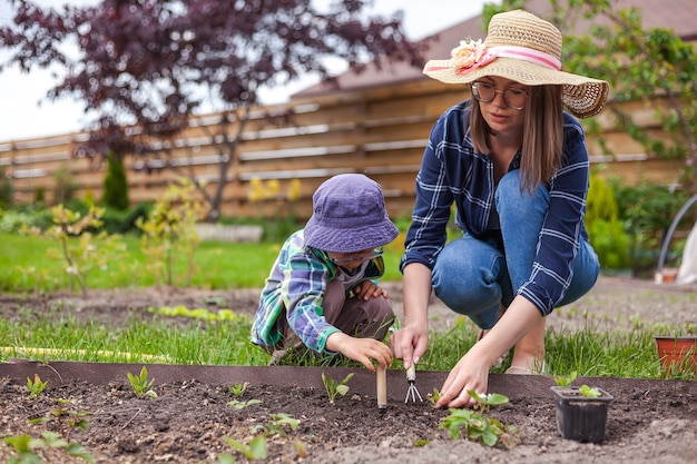 Niño y madre jardinería en huerto en el patio trasero