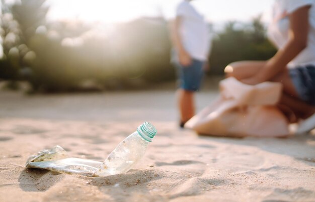 Niño con madre recoge basura plástica en la playa junto al mar Botellas de plástico sucias usadas vacías