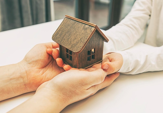 El niño y la madre sostienen el concepto de adopción de la casa de juguetes de madera