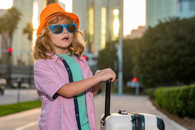 Niño con maleta de viaje de vacaciones Concepto de viaje y aventura para niños Niño pequeño que se va de vacaciones con equipaje bolsa de viaje al aire libre