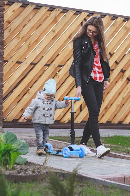 Niño y mamá juegan al aire libre con scooter