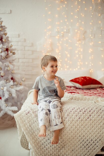 Niño de la mañana de Navidad sentado en la cama