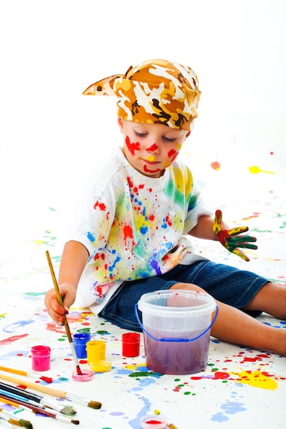 Un niño manchado de pintura dibuja