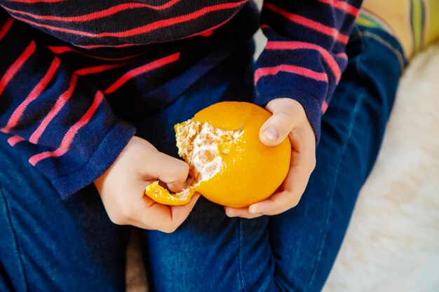 Niño y mandarina. Enfoque selectivo comida y bebida.