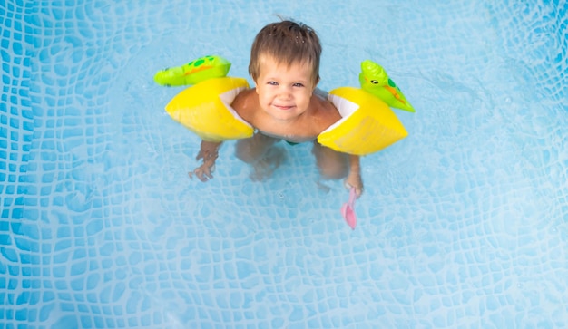 Niño en mangas largas nada en la piscina en el patio