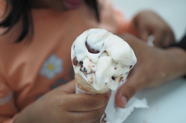 Niño mano sosteniendo helado de vainilla en un cono de galleta