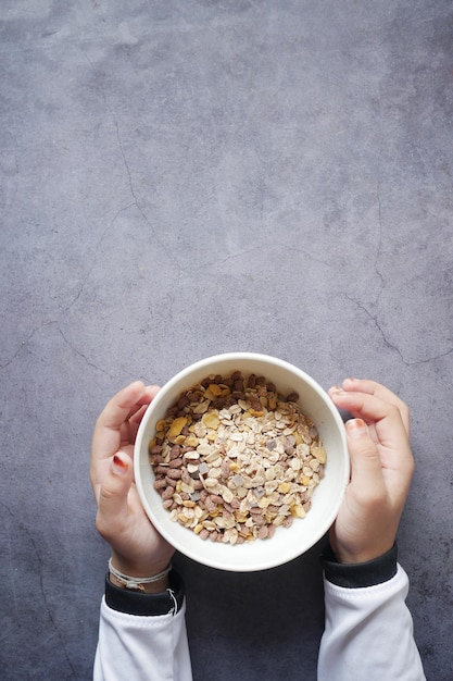 Niño mano sosteniendo un tazón de cereal de desayuno Musli