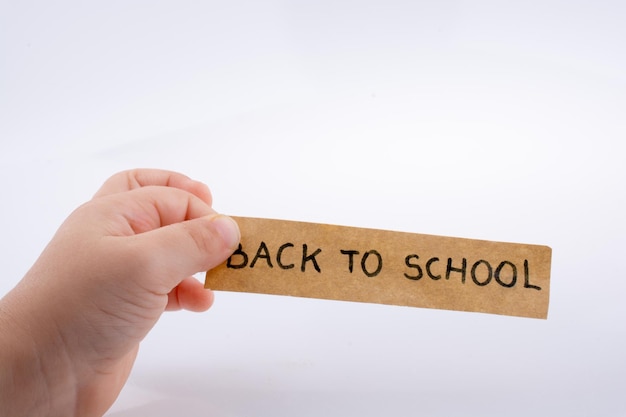 Niño con la mano sosteniendo un título de regreso a la escuela