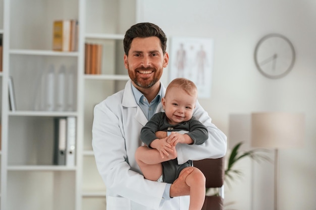 Foto con el niño en las manos el doctor con el bebé está trabajando en el gabinete