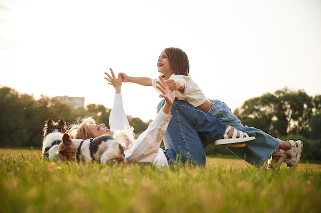 Foto el niño está en manos de la mujer hermosa madre con su hija pequeña y los perros están en el campo de verano juntos