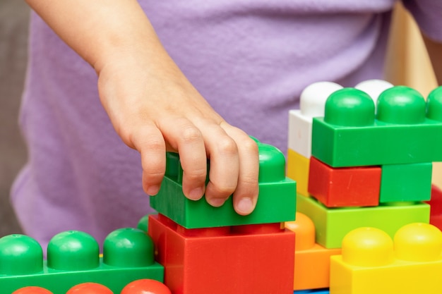 Niño, manos de niño, mientras juega con el constructor de bloques de juguete educativo