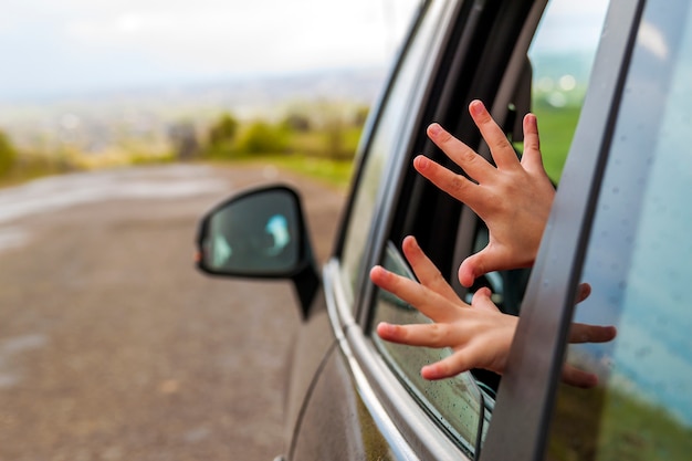 Niño manos en la ventanilla de un automóvil durante el viaje a las vacaciones