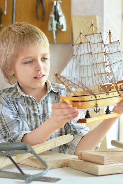 Niño con maqueta de barco y serrucho