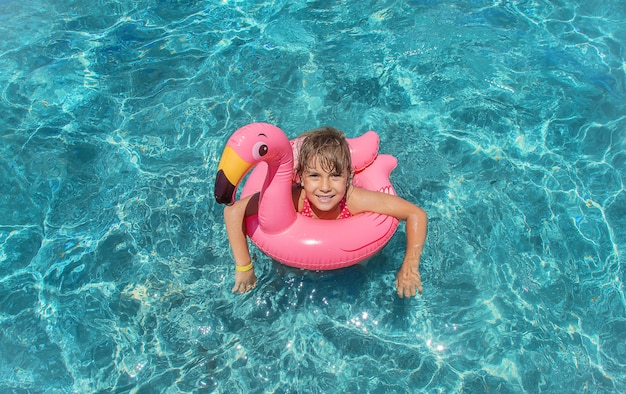 Niño en el mar descansando con flamingo toy