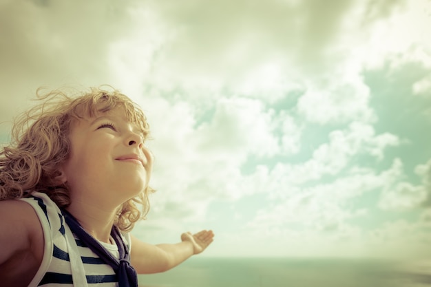 Niño marinero mirando hacia el futuro contra el cielo de verano