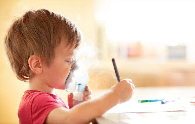 un niño con una máscara de inhalación está dibujando en una mesa