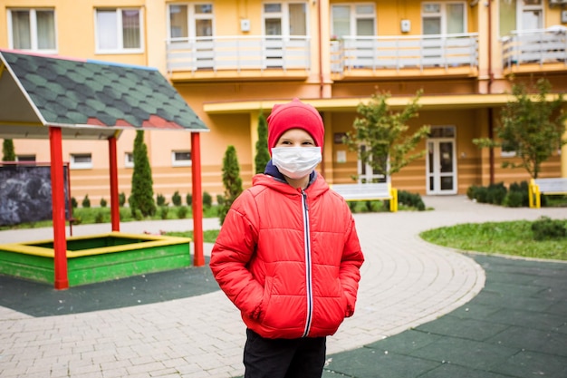 Niño con máscara médica camina solo cerca del patio de recreo Distancia social durante la pandemia