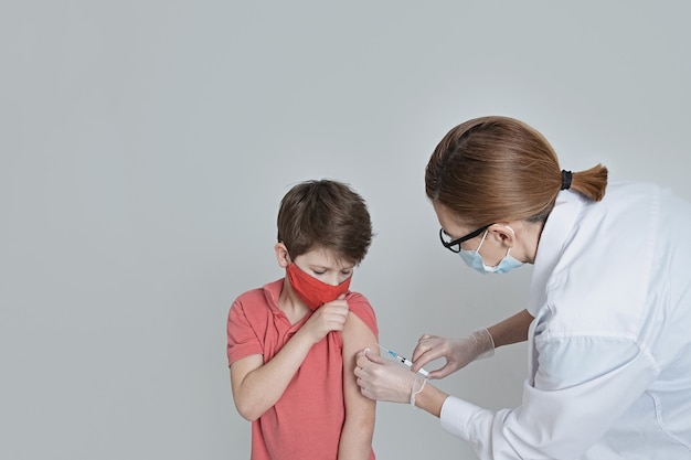 Un niño con máscara médica está vacunado contra el coronavirus en la pandemia de covid