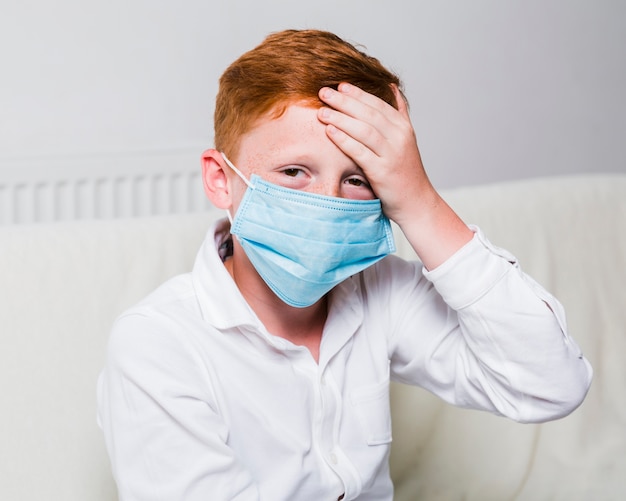 Foto niño con mascarilla y dolor de cabeza