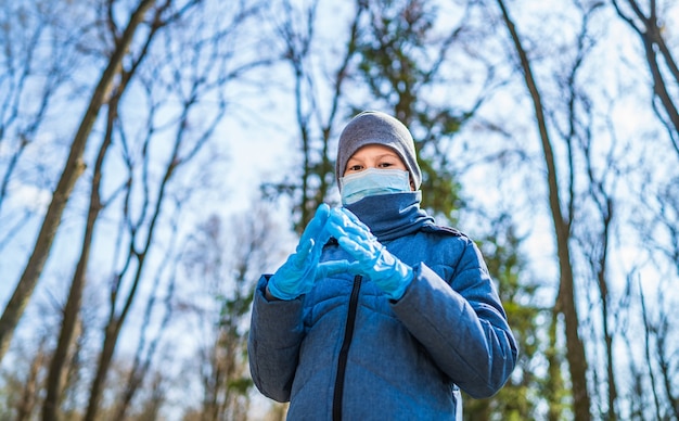 Niño con mascarilla. Mascarilla para protección frente al brote del virus corona. Niño al aire libre en el parque de primavera en guantes médicos estériles.