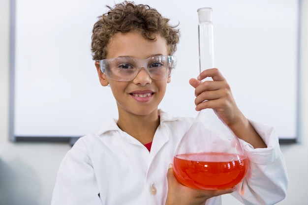 Niño con matraz con líquido en el laboratorio en la escuela