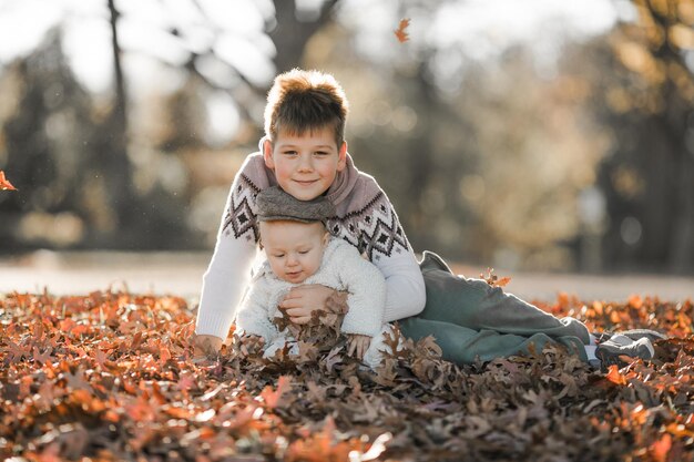 el niño mayor abraza y se comunica con su hermano de 6 meses de edad los niños sentados en el parque pasan tiempo juntos