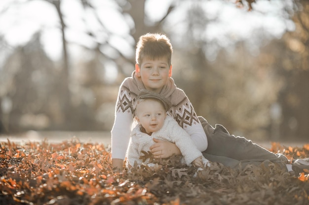 el niño mayor abraza y se comunica con su hermano de 6 meses de edad los niños sentados en el parque pasan tiempo juntos