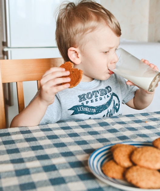 El niño en la mesa toma una pequeña mano galletas de avena