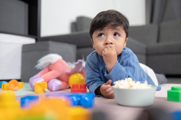 Niño mexicano de dos años comiendo palomitas de maíz en una habitación desordenada