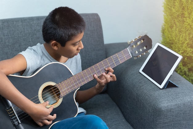Niño mexicano tomando lecciones de guitarra en casa debido al encierro por coronavirus, educación en casa