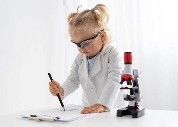 Niño con microscopio y gafas de seguridad.