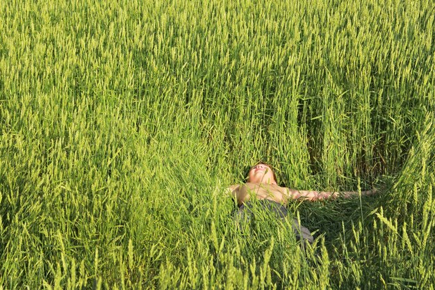 El niño miente y descansa entre el campo de trigo Vacaciones en la naturaleza