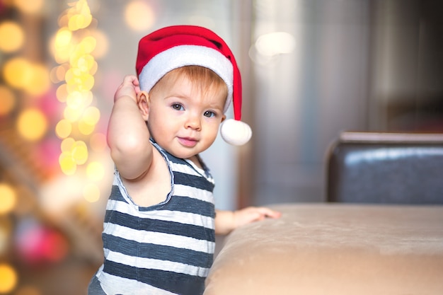 El niño mira a la cámara y corrige el dibujo de Papá Noel esperando un milagro.