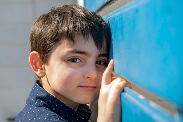 Niño mira en cámara valla de madera azul