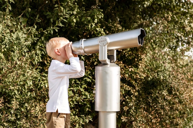 Niño mira en un gran telescopio Observación de la naturaleza a través de un telescopio