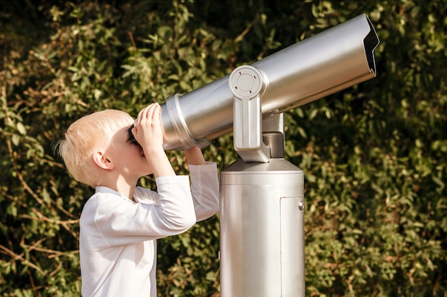 Niño mira en un gran telescopio Observación de la naturaleza a través de un telescopio