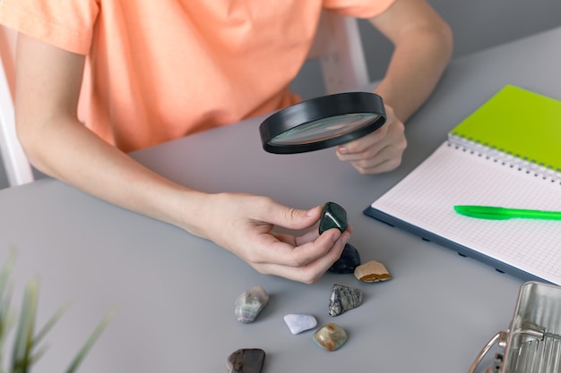 El niño mira su colección de piedras semipreciosas con lupa Concepto de educación